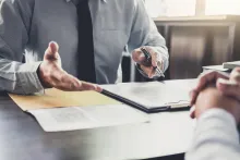 Two people talking over a desk with paperwork in between them